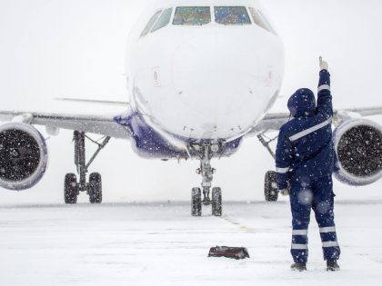 Man directing plane on the ground in snowy conditions