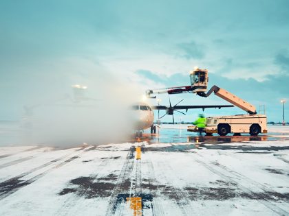 Machine deicing a plane on airport runway in the snow